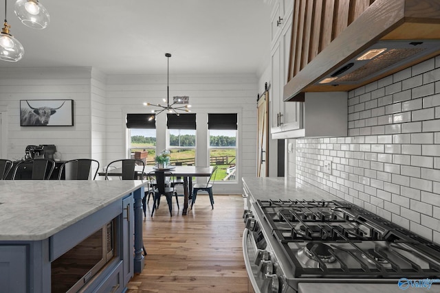 254 Whitlow Rd, Decatur, AL 35603 - kitchen featuring custom exhaust hood, stainless steel gas stove, wood finished floors, light stone counters, and a chandelier