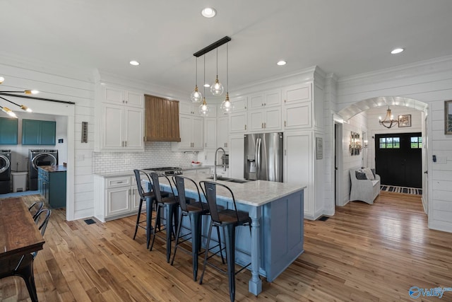 254 Whitlow Rd, Decatur, AL 35603 - kitchen featuring stainless steel fridge, washer and clothes dryer, a chandelier, white cabinets, and arched walkways