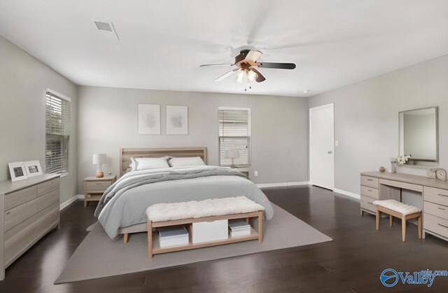 bedroom featuring dark hardwood / wood-style flooring, ceiling fan, and multiple windows