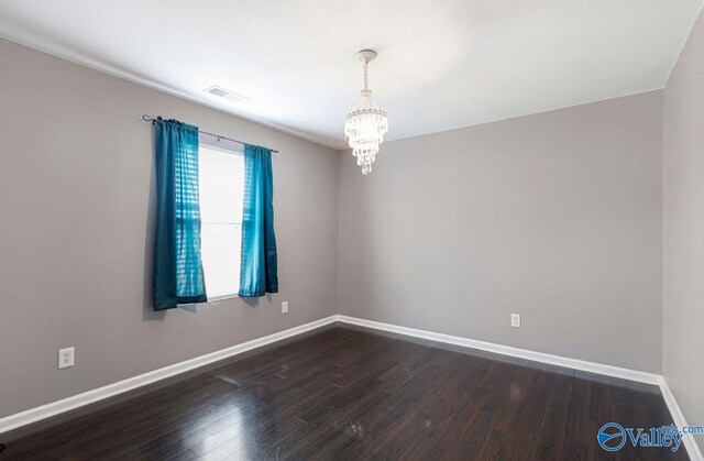 unfurnished room with dark hardwood / wood-style floors and an inviting chandelier