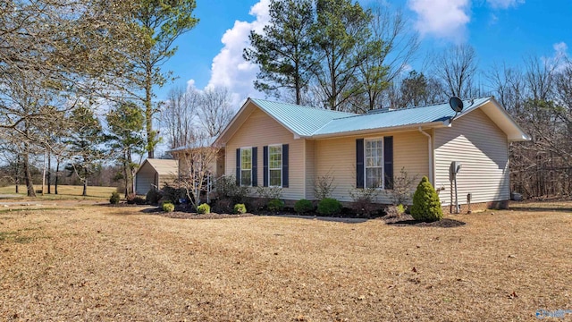 view of side of property featuring metal roof and a lawn