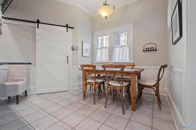 dining space with a barn door, crown molding, and light tile patterned flooring