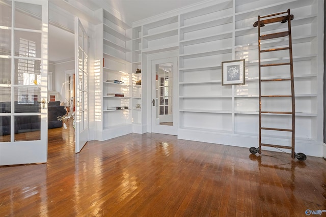 interior space featuring wood-type flooring, crown molding, and built in shelves