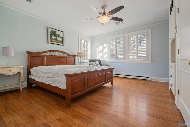 bedroom with hardwood / wood-style flooring, ceiling fan, ornamental molding, and a baseboard heating unit