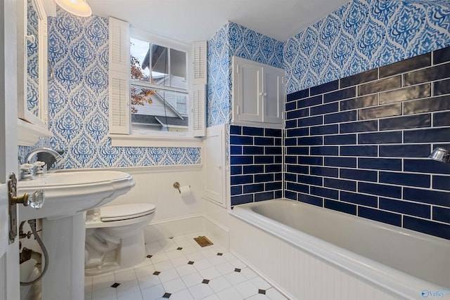 bathroom featuring tile patterned floors, a washtub, and toilet