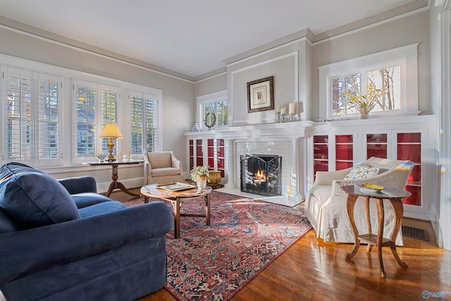 living area featuring a fireplace, hardwood / wood-style floors, and ornamental molding