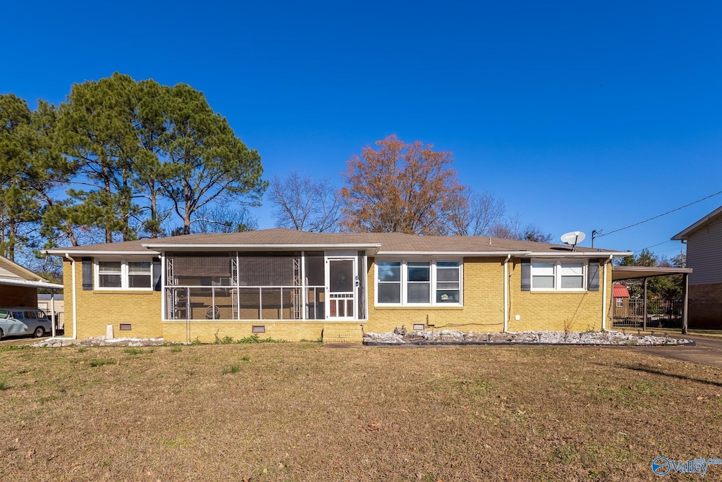 rear view of property featuring a carport, a sunroom, and a lawn