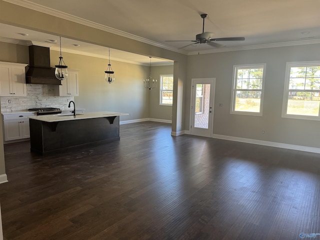 kitchen with sink, white cabinetry, a kitchen island with sink, custom range hood, and decorative light fixtures