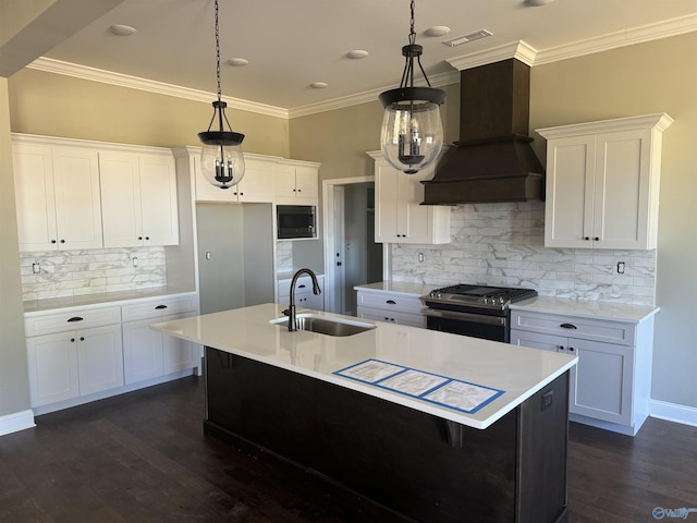 kitchen featuring stainless steel range with gas stovetop, hanging light fixtures, custom range hood, and white cabinets