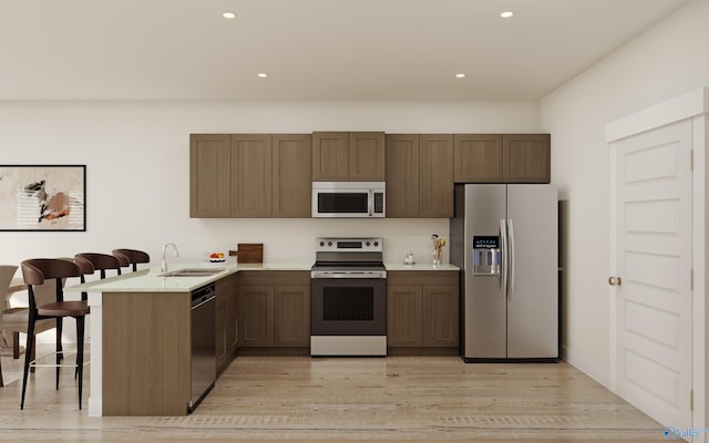 kitchen with light wood-type flooring, a sink, stainless steel appliances, a peninsula, and light countertops