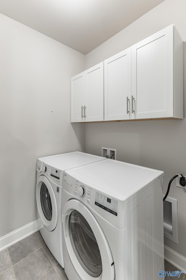 laundry area featuring tile patterned floors, cabinets, and washing machine and dryer