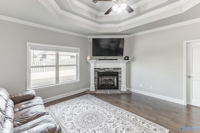 living room featuring a raised ceiling, crown molding, a fireplace, and ceiling fan