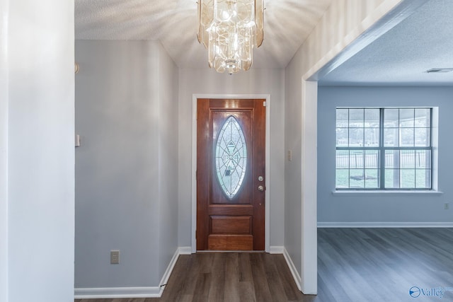 foyer entrance with a chandelier, a textured ceiling, and dark wood-type flooring