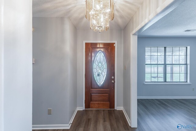 foyer entrance featuring dark wood-style floors, baseboards, a notable chandelier, and a healthy amount of sunlight