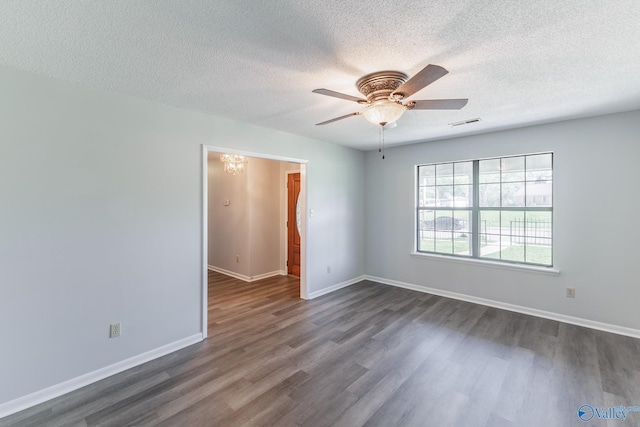 empty room with ceiling fan with notable chandelier, baseboards, visible vents, a textured ceiling, and dark wood-type flooring