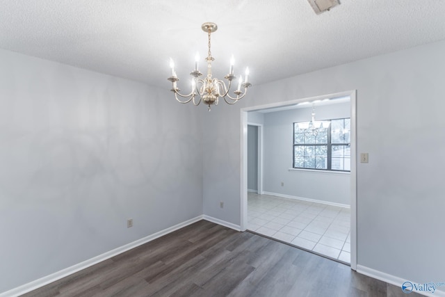 spare room featuring visible vents, an inviting chandelier, a textured ceiling, and dark wood-type flooring