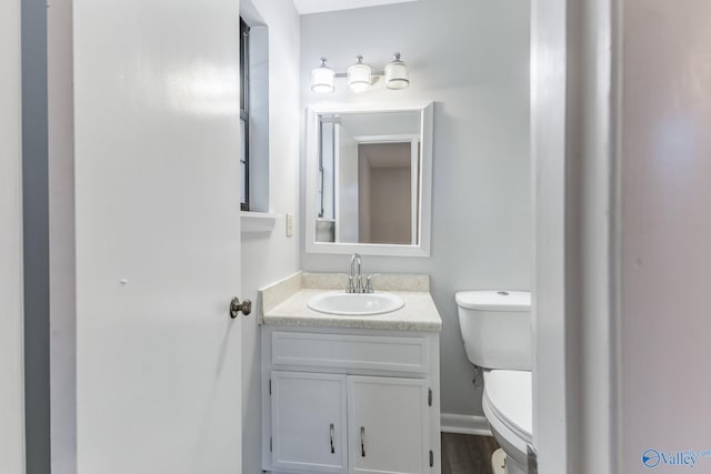 bathroom with vanity, toilet, and hardwood / wood-style flooring