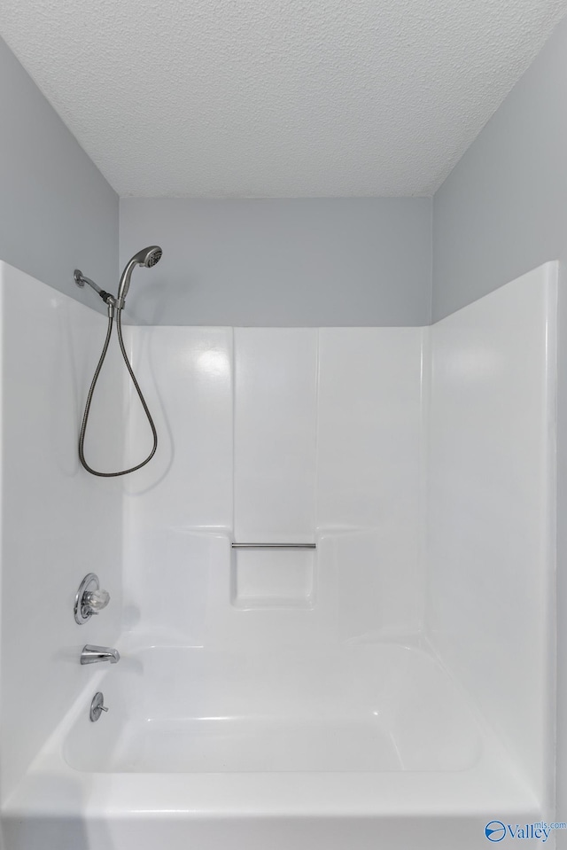 bathroom with a textured ceiling and shower / bath combination