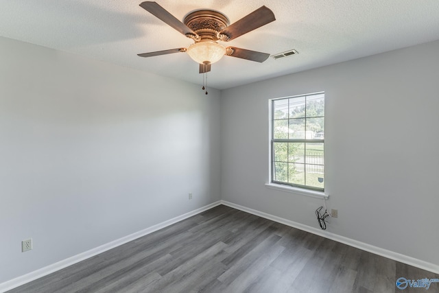 empty room featuring dark wood-style flooring, baseboards, visible vents, a ceiling fan, and a textured ceiling