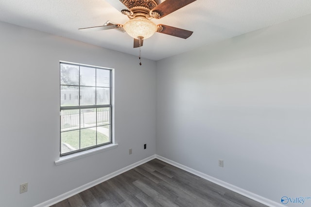 empty room featuring ceiling fan, baseboards, and dark wood finished floors