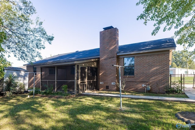 rear view of property with a sunroom, brick siding, a yard, a chimney, and fence