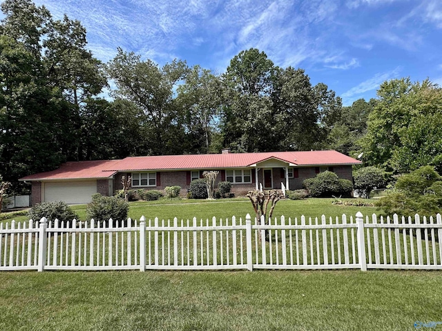 ranch-style house featuring a fenced front yard, metal roof, a front lawn, and an attached garage