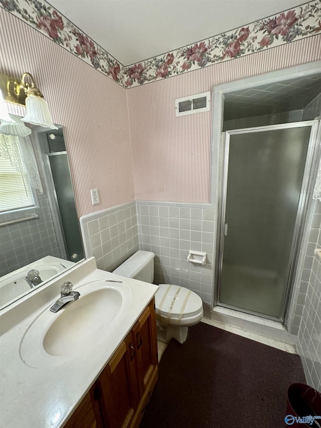bathroom featuring wallpapered walls, a wainscoted wall, and a stall shower