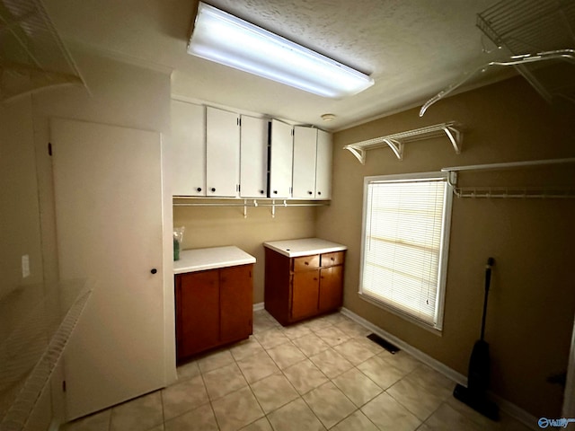 clothes washing area with a textured ceiling and light tile patterned flooring