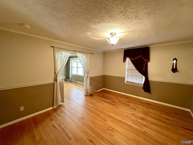 empty room featuring crown molding, baseboards, a textured ceiling, and light wood-type flooring