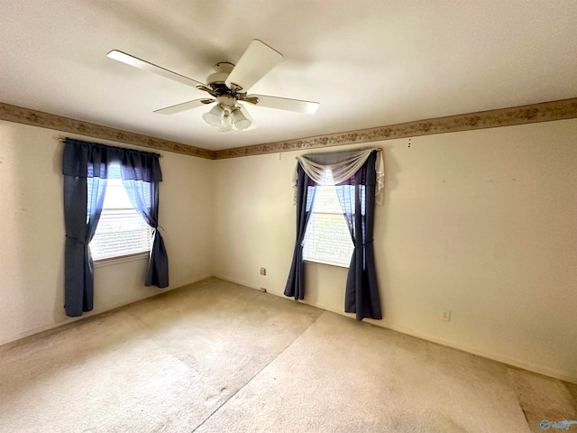 carpeted spare room with a wealth of natural light and ceiling fan