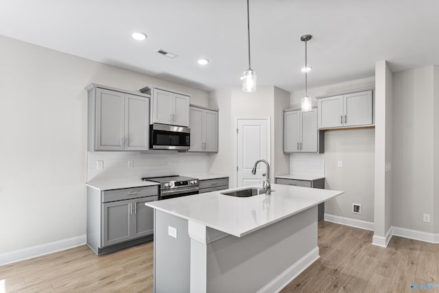 162 River Pointe Dr, New Market, AL 35761 - kitchen with gray cabinetry, a sink, backsplash, light wood-style floors, and appliances with stainless steel finishes