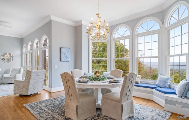 dining space with a chandelier, ornamental molding, light wood-style flooring, and baseboards