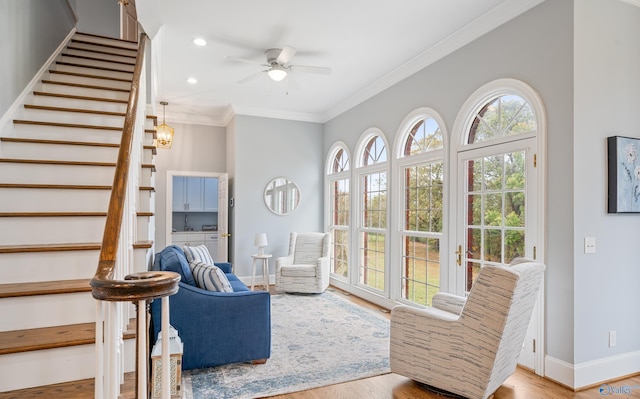 sitting room with baseboards, a ceiling fan, stairway, wood finished floors, and crown molding