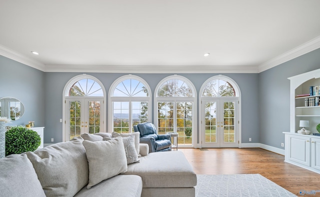 living area with light wood-style floors, french doors, crown molding, and baseboards