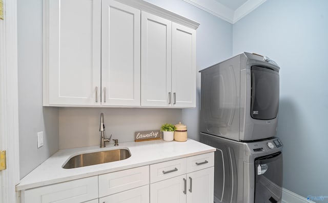 washroom featuring cabinet space, ornamental molding, a sink, and stacked washer and clothes dryer