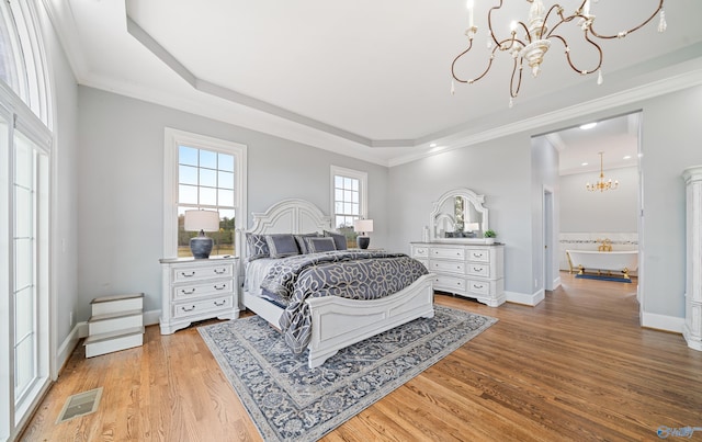 bedroom with visible vents, baseboards, a raised ceiling, light wood-style flooring, and a chandelier