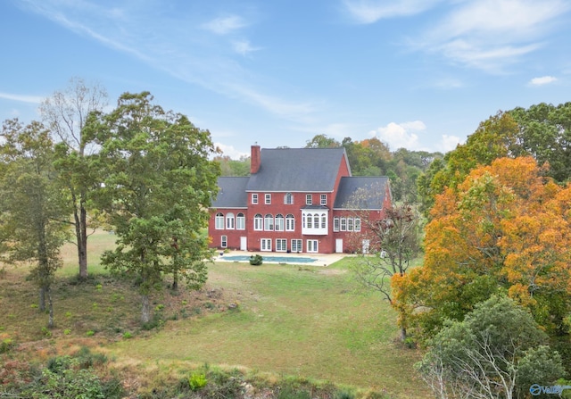 rear view of property with a chimney, a patio, and a yard