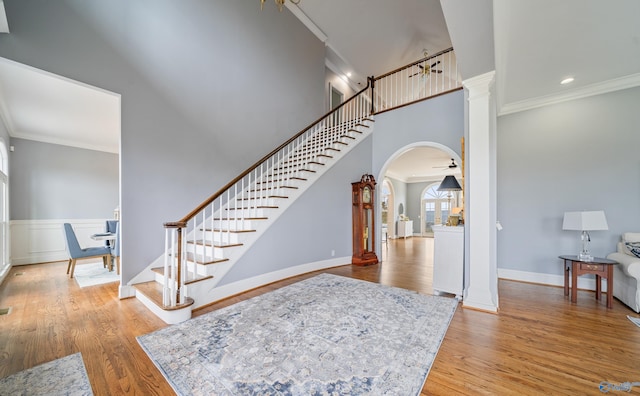 foyer entrance featuring crown molding, stairs, arched walkways, and wood finished floors