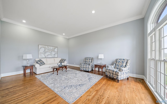 living room with light wood finished floors, ornamental molding, and a healthy amount of sunlight