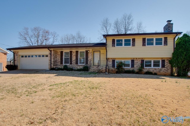 split level home featuring an attached garage, covered porch, a chimney, and brick siding