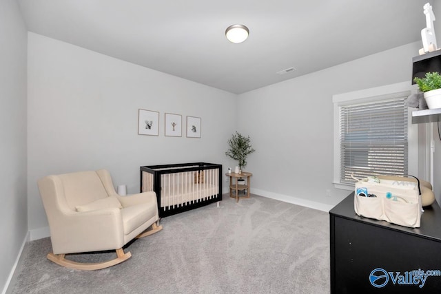 bedroom featuring a nursery area and carpet floors