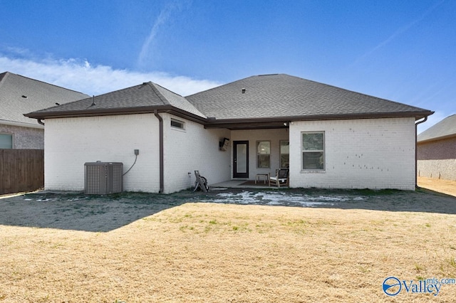 back of property with a lawn, central AC, and a patio area