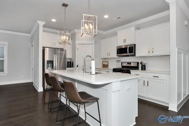 kitchen with stainless steel appliances, an island with sink, pendant lighting, white cabinets, and sink