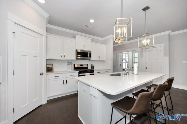 kitchen featuring hanging light fixtures, a kitchen island with sink, white cabinets, appliances with stainless steel finishes, and sink