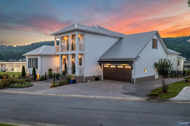 view of front of property featuring a garage, metal roof, decorative driveway, and a balcony