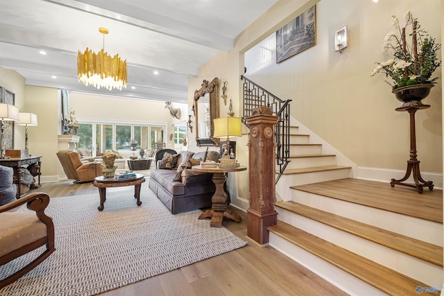 living room with beam ceiling, a chandelier, and light wood-type flooring