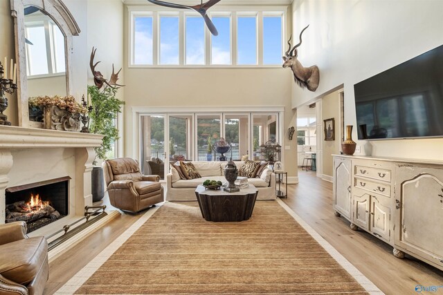 living room featuring a wealth of natural light, a fireplace, light hardwood / wood-style floors, and a towering ceiling