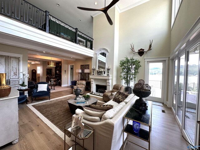 living room with hardwood / wood-style flooring, ornamental molding, ceiling fan, and a high ceiling