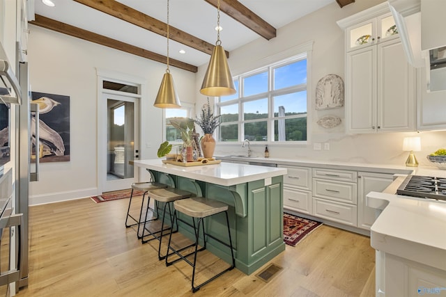 kitchen featuring white cabinets, pendant lighting, a center island, and light wood-type flooring