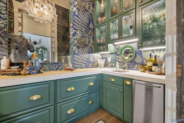 bar with sink, stainless steel dishwasher, green cabinetry, and hardwood / wood-style flooring